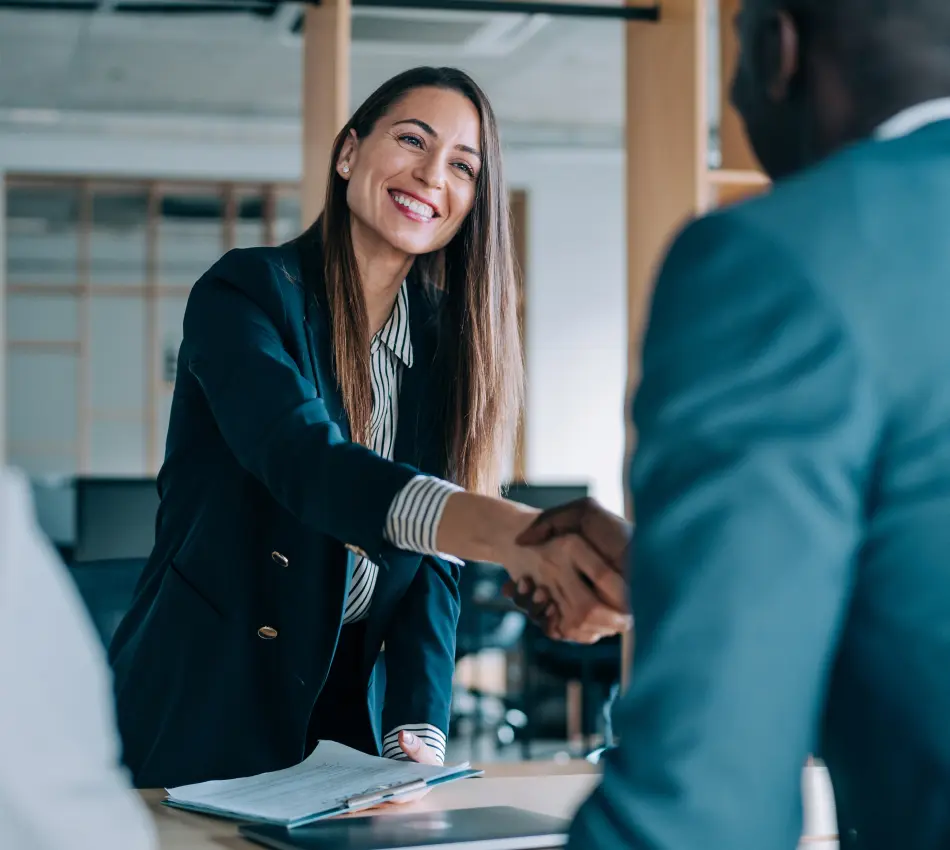 Female hiring manager holding a clipboard and shaking hands with a male candidate.