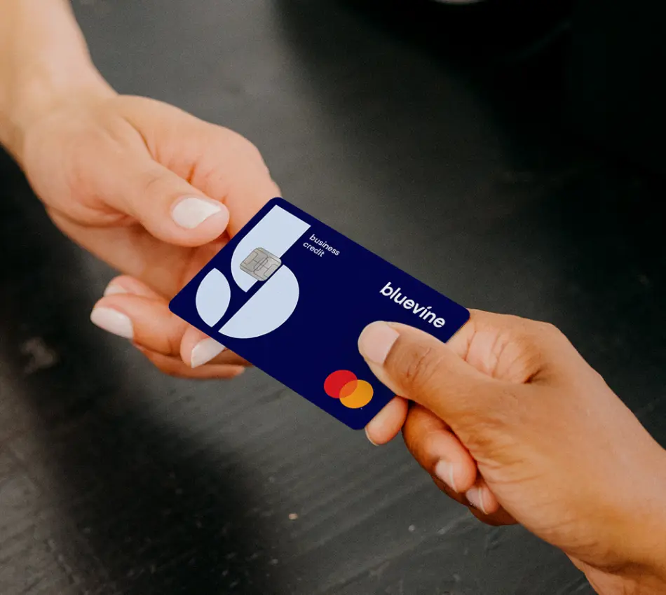 Small business owner hands Bluevine Business Cashback Mastercard to a cashier.
