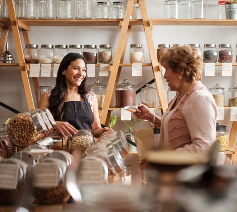 Young Hispanic shop owner helping an older customer in her store