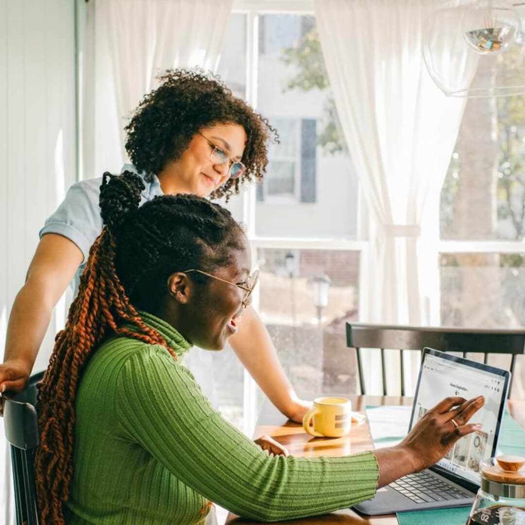 Two young Black female business owners looking business checking sub-accounts on their computer