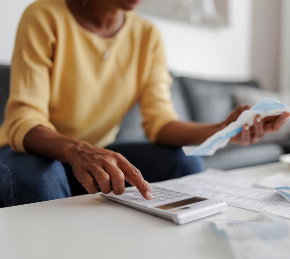 Business owner holds a paper invoice and uses a calculator.