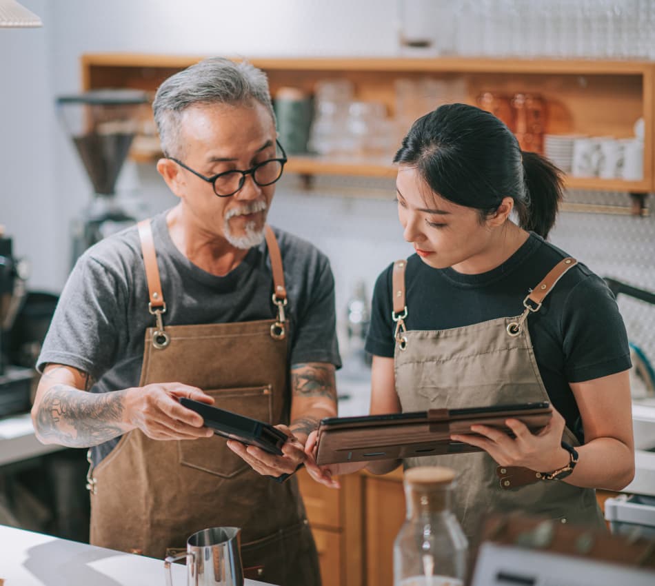 Shop owners look at business expansion plans on their tablets.