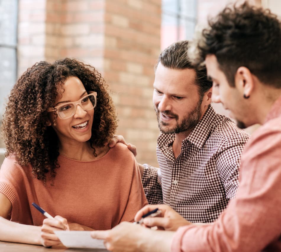 Three business partners talk while looking over paperwork.