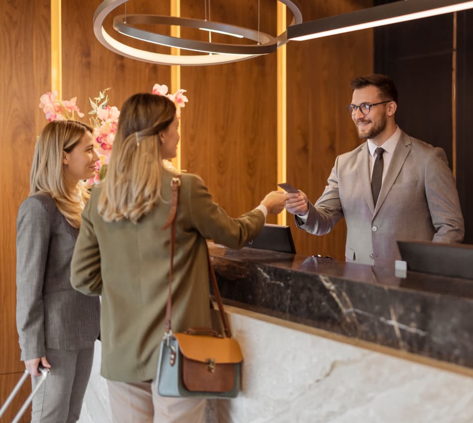 A front desk hotel employee welcomes guests.