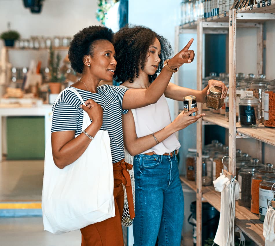 Two shoppers search for sustainable products in boutique shop.