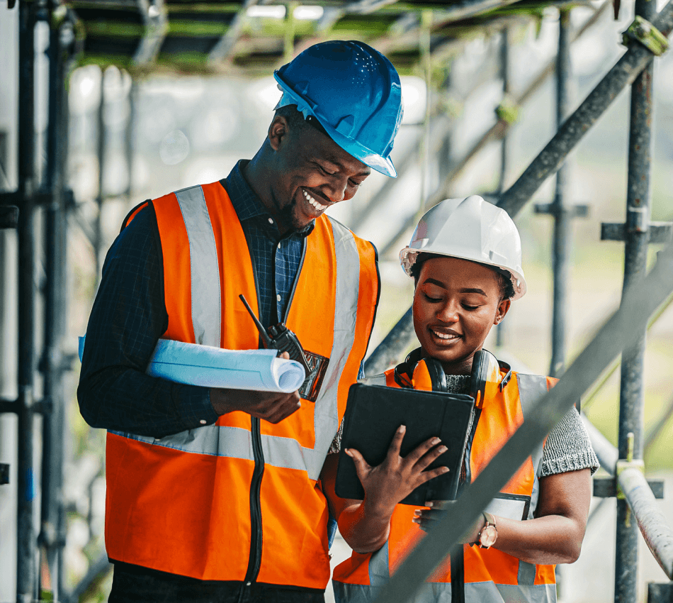 Contractor in hardhat and vest reviewing construction timeline with tablet on site.