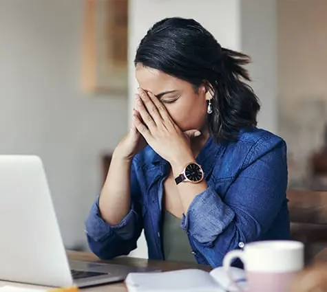 Image of stressed young female business owner sitting at her computer with hands on face