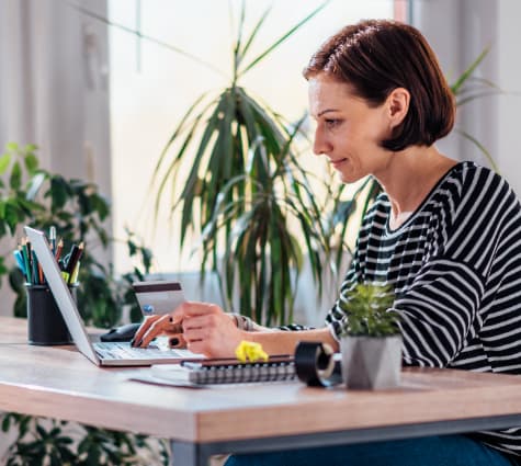 Image of woman looking at computer and paying something with her credit card