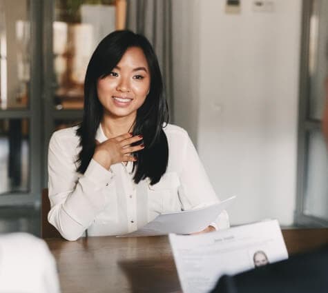 Young Asian woman in a white blouse speaking with a man and woman during an interview