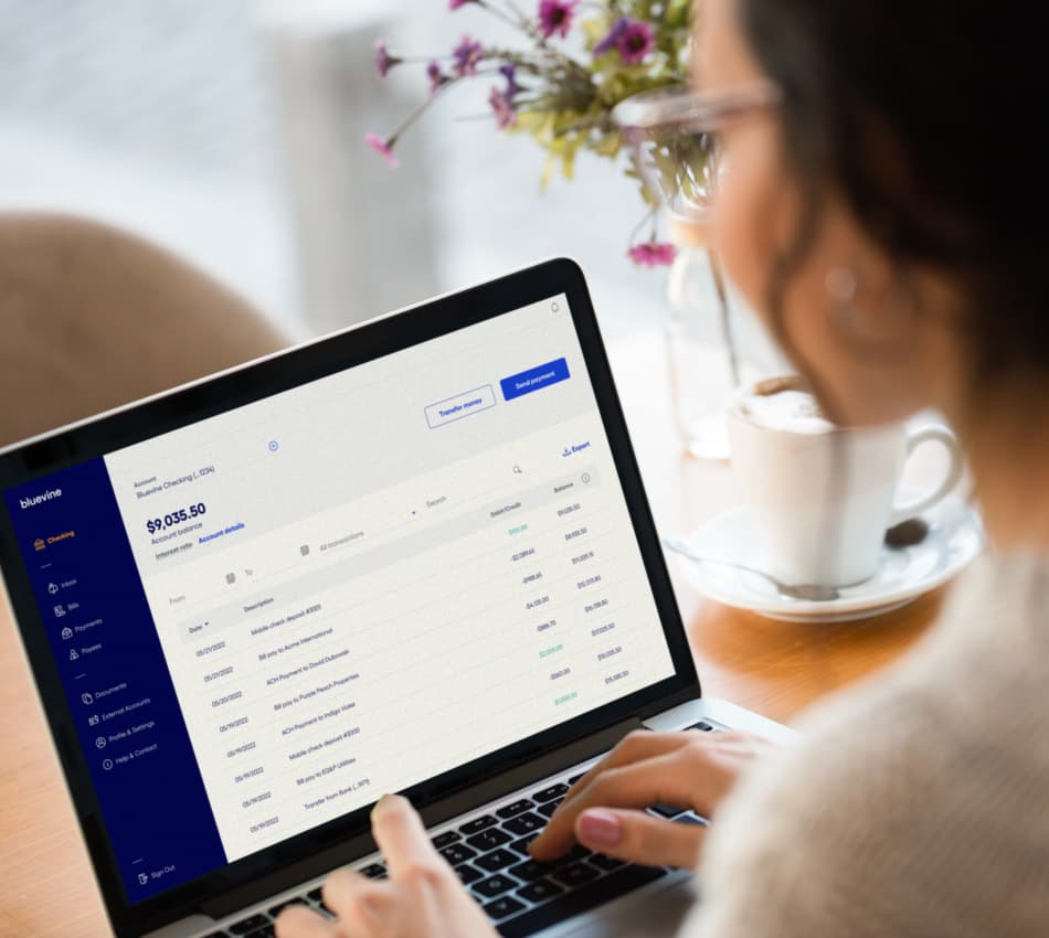 Over-the-shoulder view of woman accessing her Bluevine Business Checking account from her laptop.