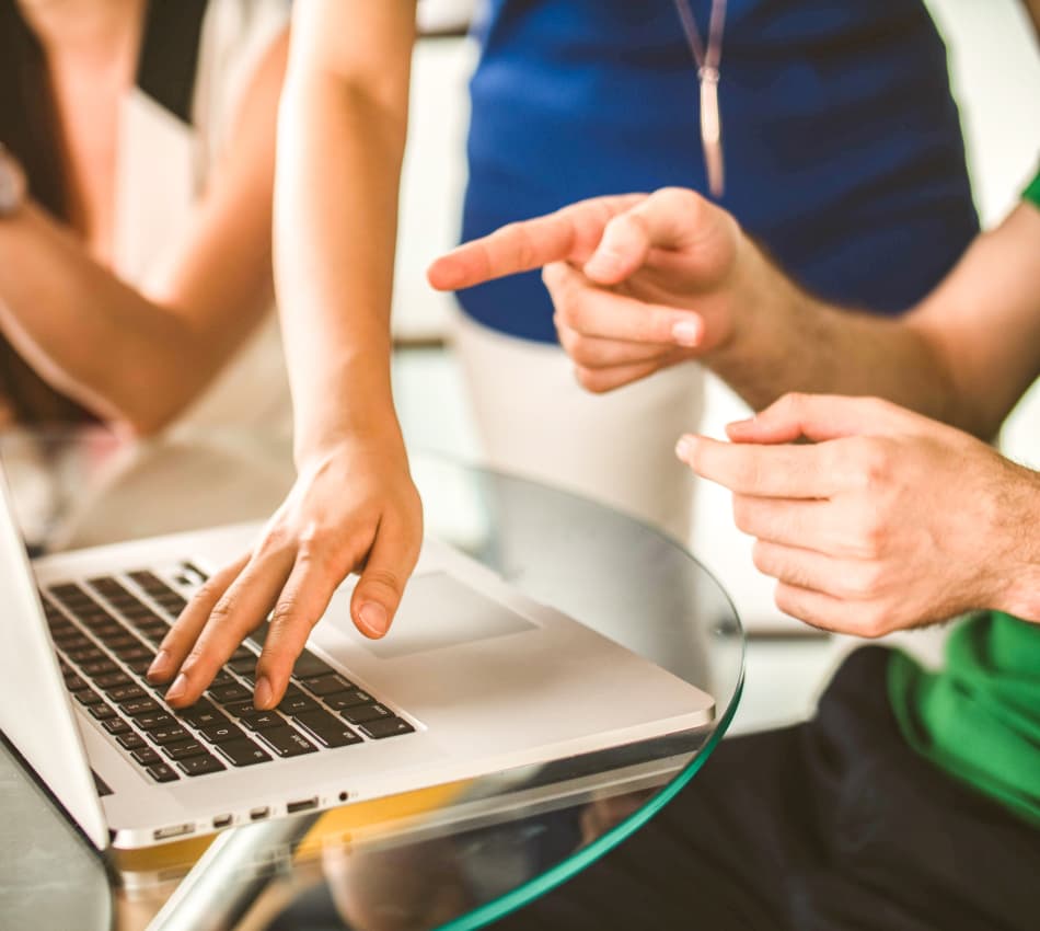 Close-up on hands pointing at a laptop as a team discusses customer experience.
