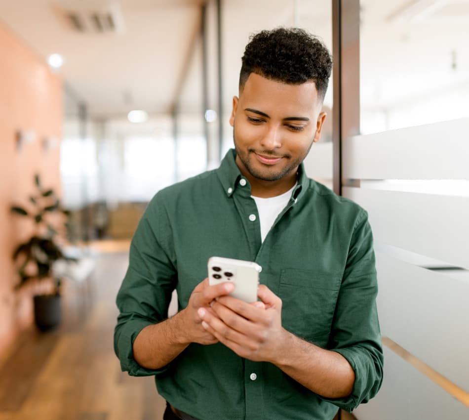 Man in office smiles at his phone after receiving an SMS marketing message.