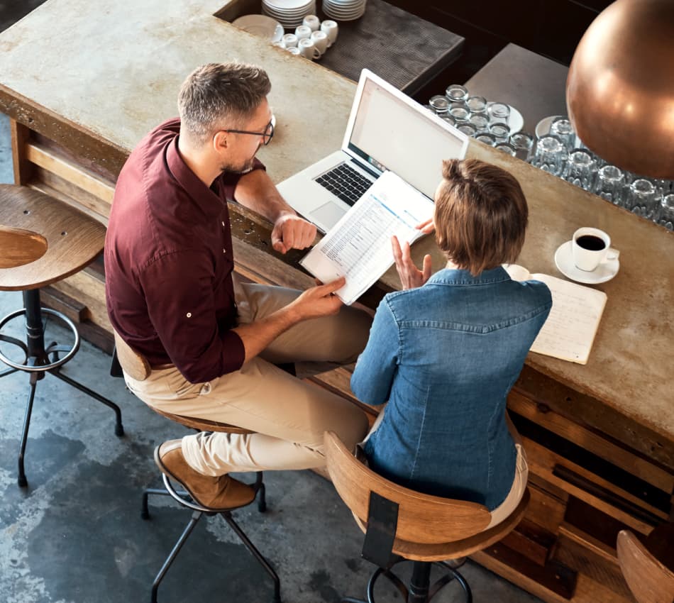Two small business owners sit at a table and develop their franchising plan.
