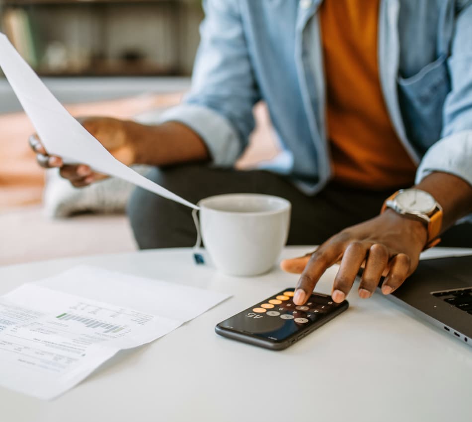 Close-up of a business owner using a calculator while holding papers.