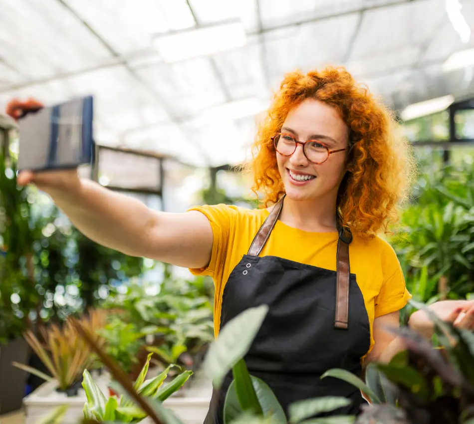 Woman at garden center takes selfie to promote business with user-generated content (UGC).