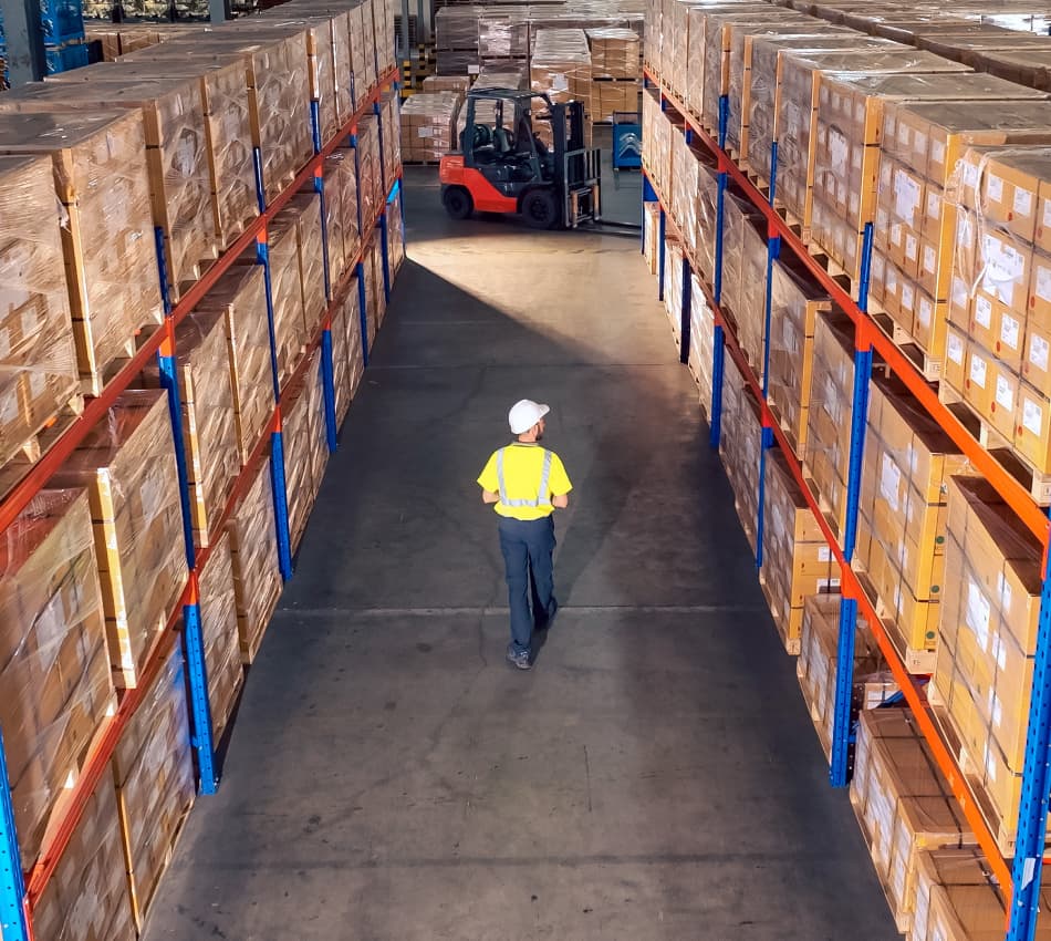 Man in hard hat walks through warehouse space.