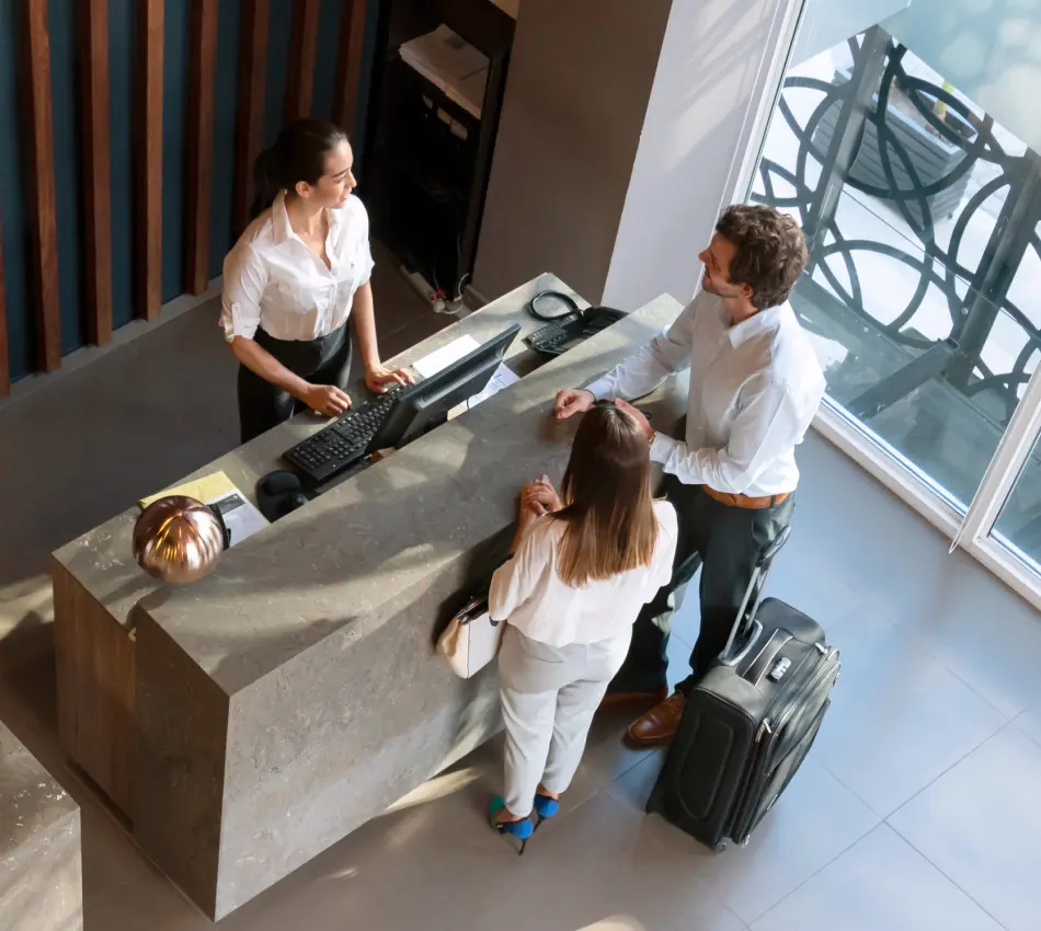 Overhead photo of a couple checking in at the front desk of a hotel.