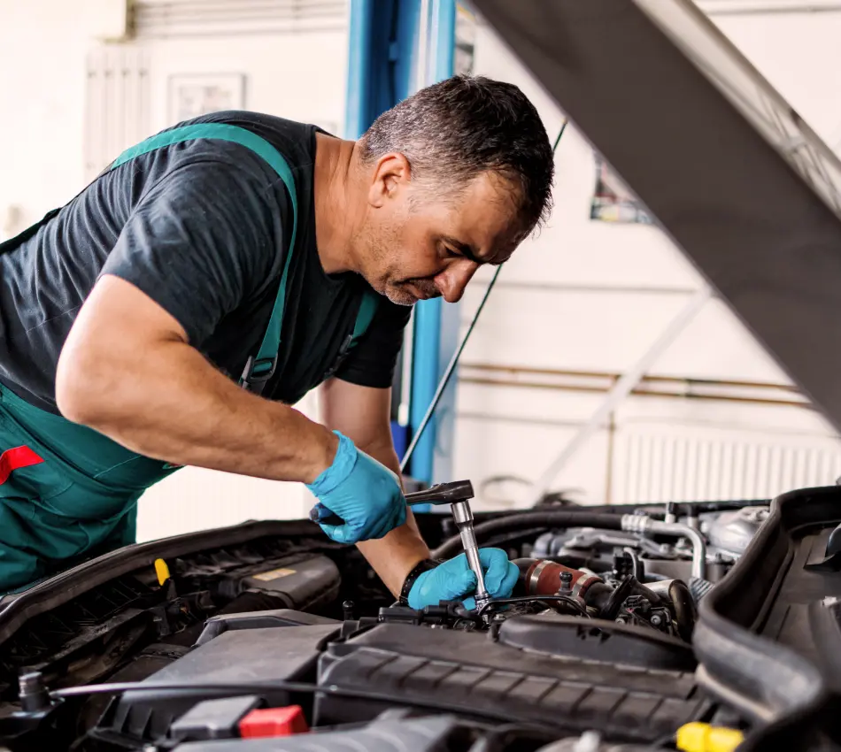 Mechanic works on car at auto repair shop.