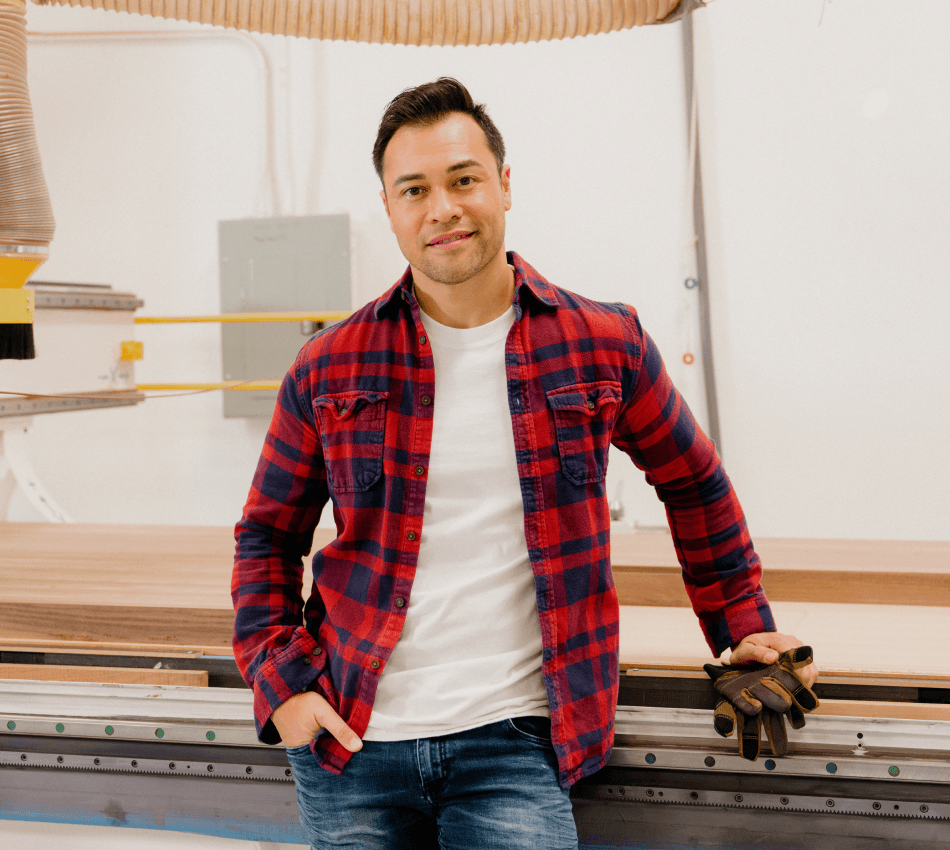 Construction business owner stands in front of a machine while holding gloves.